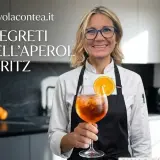 Donna sorridente con un bicchiere di Spritz Aperol, guarnito con arancia. Scopri i segreti degli ingredienti Spritz Aperol perfetti.