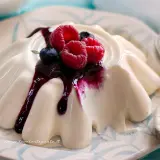 Deliziosa panna cotta con frutti di bosco e salsa ai mirtilli, servita su un piatto decorato.