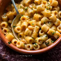 Un piatto fumante di pasta e fagioli, con ditalini e fagioli cannellini in un sugo cremoso, guarnito con prezzemolo tritato.