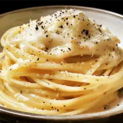 Un piatto di spaghetti cacio e pepe, cremosi e ricchi di pecorino romano e pepe nero macinato fresco.