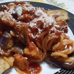 Un piatto invitante di pasta con melanzane, condita con sugo rosso e abbondante formaggio grattugiato.