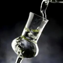 Versando grappa in un bicchiere speciale, creando bollicine e un'atmosfera invitante.