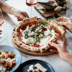 Un delizioso abbinamento pizza con cipolla, accompagnato da un fresco rosato e un'insalata di prosciutto.