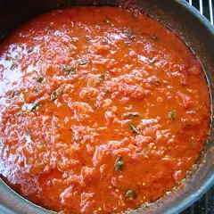 Sugo di pomodoro fresco in padella, profumato con erbe aromatiche, pronto per condire la pasta.
