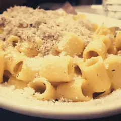 Piatto di carbonara fumante, cosparso di pecorino e pepe. Perfetta con un bicchiere di vino bianco o rosso.