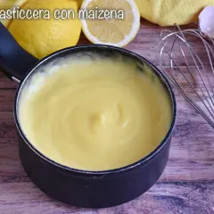 Crema pasticcera liscia e vellutata, preparata con amido di mais, pronta per farcire dolci. Accanto, limoni e gusci d'uovo.
