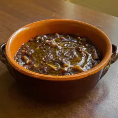 Una ciotola di terracotta con un saporito piatto di pasta e lenticchie, condito con olio d'oliva.