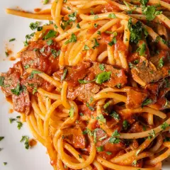 Spaghetti con tonno in scatola, un classico piatto veloce e saporito, condito con sugo di pomodoro e prezzemolo fresco.
