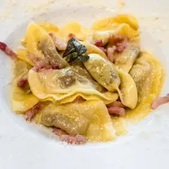 Piatto di casoncelli alla bergamasca con pancetta e salvia, spolverati di formaggio grattugiato.