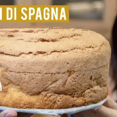 Un soffice pan di spagna senza glutine, dorato e invitante, tenuto da mani sorridenti.