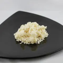 Un mucchietto di riso bianco cotto su un piatto nero, pronto per essere gustato. Ecco come cuocere il riso per un risultato perfetto.