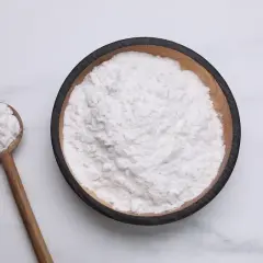 Una ciotola di amido di riso per dolci, con un cucchiaio di legno pieno dello stesso ingrediente soffice.