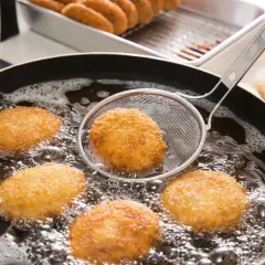 Crocchette dorate che sfrigolano nell'olio bollente, un perfetto esempio di come friggere per ottenere una croccantezza irresistibile.