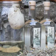 Vaso con infuso di erbe e due bottiglie di genepy, pronti per la ricetta.