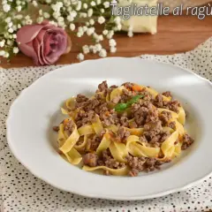 Tagliatelle al ragù bianco, un piatto gustoso con carne macinata e verdure, guarnito con basilico.