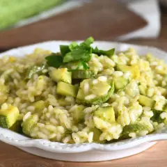 Un cremoso risotto con zucchine, guarnito con prezzemolo fresco, servito in un piatto bianco.
