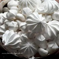 Un cesto pieno di meringhe soffici, perfette per la tua ricetta. Dolci e leggere, invitano a essere gustate.