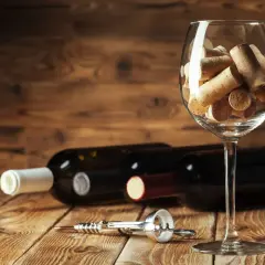 Tappi di sughero in un calice, bottiglie di vino e cavatappi sul tavolo. Un promemoria visivo su come chiudere una bottiglia di vino.