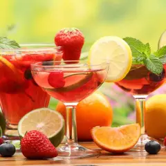 Rinfrescante aperitivo con frutta: cocktail rossi, fragole, ciliegie, mirtilli, limoni e menta.
