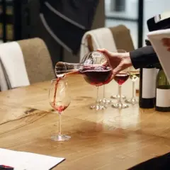 Un sommelier versa il vino rosso in un bicchiere, mostrando cosa fa un sommelier: un'arte di degustazione e servizio.