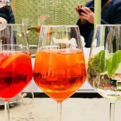 Tre spritz colorati, uno rosso con arancia, uno arancione e uno bianco con lime e menta. Perfetti per un aperitivo con il giusto grado alcolico.