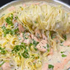 Un primo piatto cremoso di pasta panna e salmone, guarnito con prezzemolo fresco.