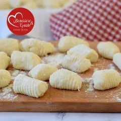 Gnocchi di ricotta freschi, pronti per essere cucinati, spolverati di farina su un tagliere di legno.