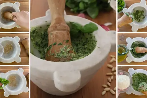 Preparazione del pesto alla genovese nel mortaio: basilico, aglio, pinoli, parmigiano e olio d'oliva si uniscono per un sapore autentico.