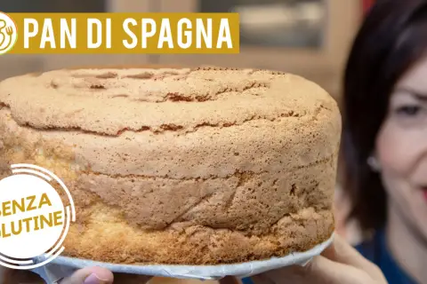 Un soffice pan di spagna senza glutine, dorato e invitante, tenuto da mani sorridenti.