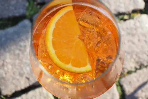 Un bicchiere di Aperol Spritz rinfrescante con ghiaccio e una fetta d'arancia, pronto per un momento di relax.