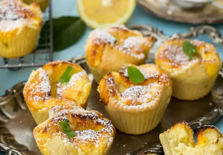 Deliziosi tortini di budino di riso, spolverati di zucchero a velo e guarniti con menta fresca, su un vassoio d'argento.