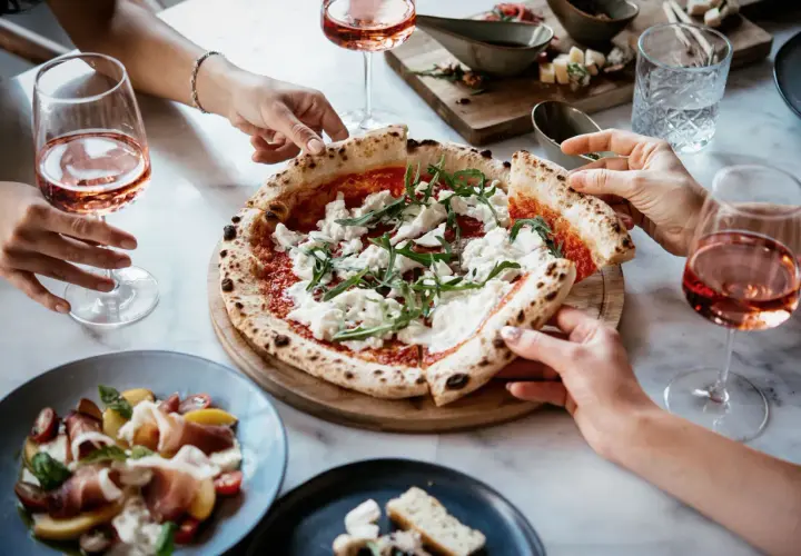 Un delizioso abbinamento pizza con cipolla, accompagnato da un fresco rosato e un'insalata di prosciutto.