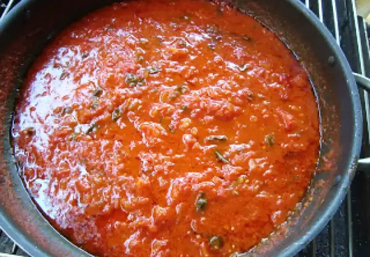 Sugo di pomodoro fresco in padella, profumato con erbe aromatiche, pronto per condire la pasta.