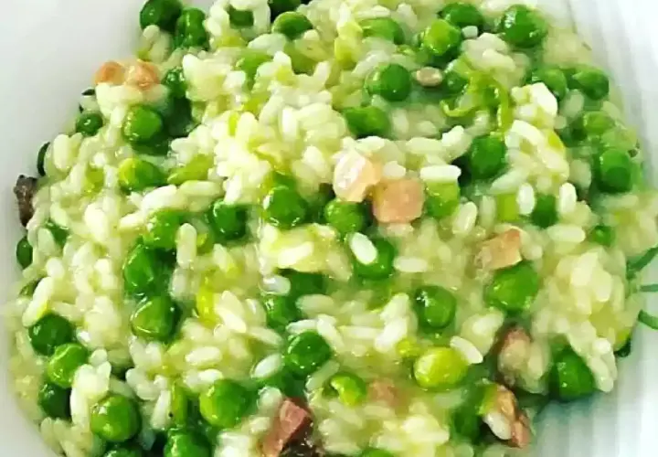 Un cremoso piatto di risi e bisi, con piselli verdi brillanti e cubetti di pancetta croccante, pronto per essere gustato.