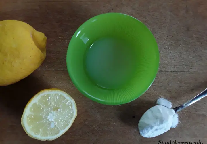 Limoni, succo di limone in ciotola verde e un cucchiaino di bicarbonato al posto del lievito per dolci.