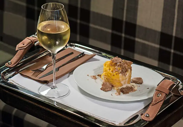 Un bicchiere di vino bianco e un piatto di pasta condita con abbondante tartufo. Un perfetto abbinamento vino tartufo per un'esperienza gourmet.