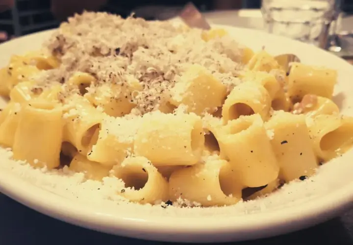 Piatto di carbonara fumante, cosparso di pecorino e pepe. Perfetta con un bicchiere di vino bianco o rosso.