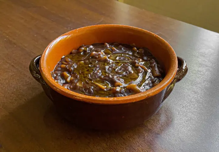 Una ciotola di terracotta con un saporito piatto di pasta e lenticchie, condito con olio d'oliva.