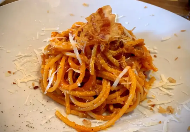 Spaghetti all'amatriciana, un classico piatto romano, perfetto con un vino rosso corposo. Guarnito con guanciale croccante e pecorino.