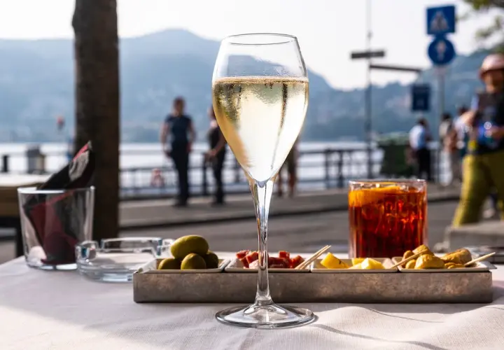 Un bicchiere di bollicine e stuzzichini, il vero significato di aperitivo in riva al lago.