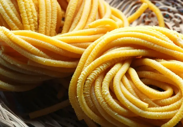 Pici all'aglione, pasta fresca fatta a mano, arrotolata in un cesto di vimini, pronta per essere gustata.