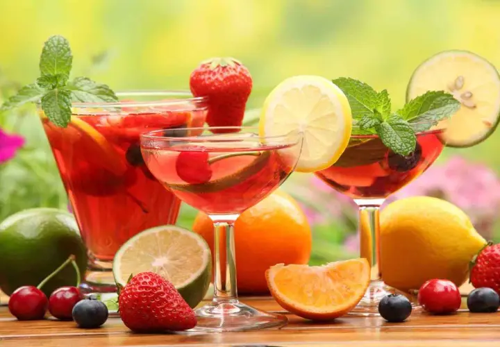 Rinfrescante aperitivo con frutta: cocktail rossi, fragole, ciliegie, mirtilli, limoni e menta.