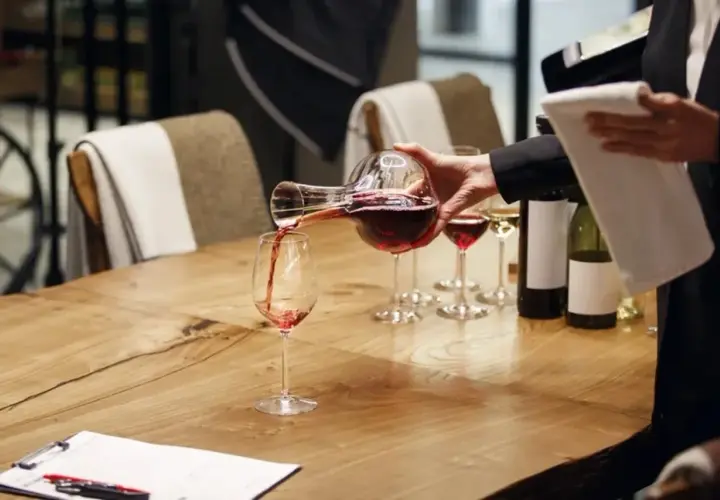 Un sommelier versa il vino rosso in un bicchiere, mostrando cosa fa un sommelier: un'arte di degustazione e servizio.