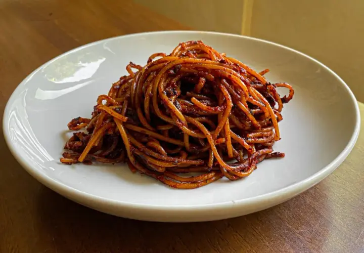 Un piatto di spaghetti all'assassina, conditi con un sugo rosso piccante e saporito, pronti per essere gustati.