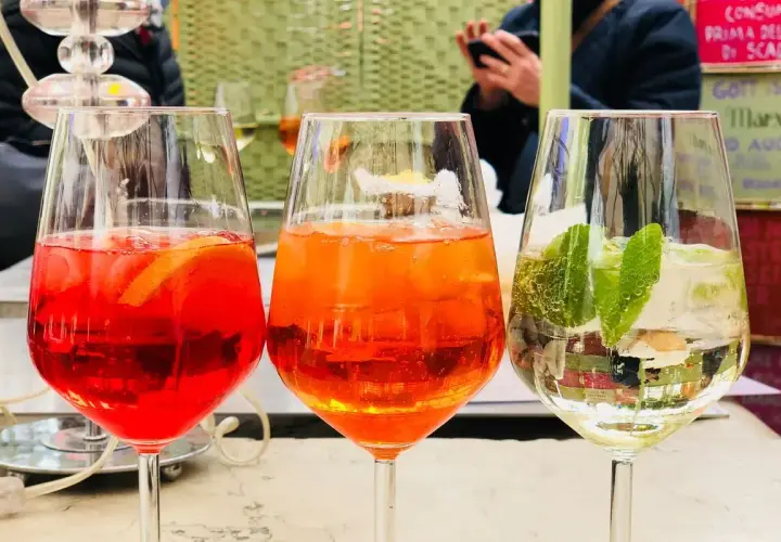 Tre spritz colorati, uno rosso con arancia, uno arancione e uno bianco con lime e menta. Perfetti per un aperitivo con il giusto grado alcolico.