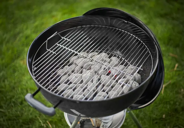 Carbone pronto per accendersi, quanta carbonella per una grigliata perfetta! La griglia è posizionata sopra, in attesa di cibo succulento.
