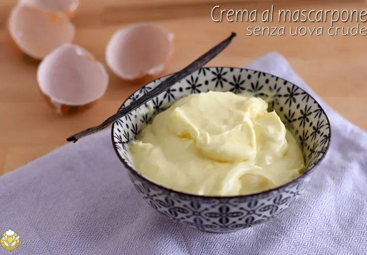 Crema al mascarpone senza uova, soffice e vellutata, servita in una ciotola decorata con un baccello di vaniglia. Guscio d'uovo sullo sfondo.