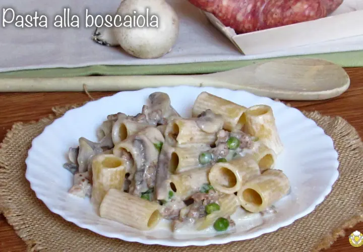 Piatto di pasta alla boscaiola con funghi, piselli e salsiccia, servita su un piatto bianco con un tovagliolo di juta.