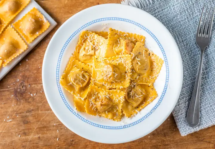 Tortelli di zucca ricetta originale, un piatto invitante con pasta fresca ripiena, condita con parmigiano e pepe nero.