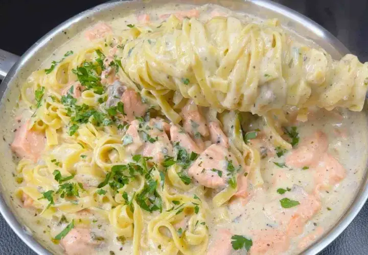 Un primo piatto cremoso di pasta panna e salmone, guarnito con prezzemolo fresco.
